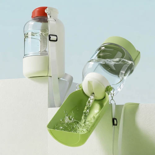 Portable dog water bottle with attached bowl, green and white, water pouring into the trough